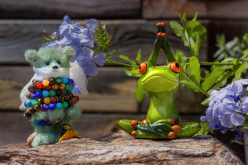 A frog doing yoga and a teddy bear being bound by a bracelet of prayer beads