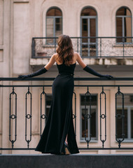 Mysterious silhouette of an elegant retro woman. A lady in long black evening dress stands on the...