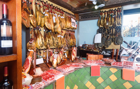 Assortment of traditional Spanish meat shop with dangling legs jamon and packings of sliced ham
