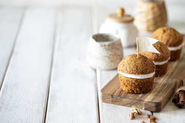 Fototapeta premium Carrot muffins with nuts and cream on a white plate. Vegan muffins. Traditional donkey pastries. Selective focus. Copy space.