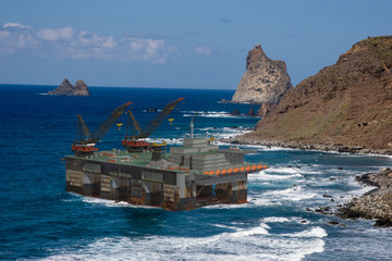 oil platform lifted by storm on rocky coast - threatened by strong winds in the seas