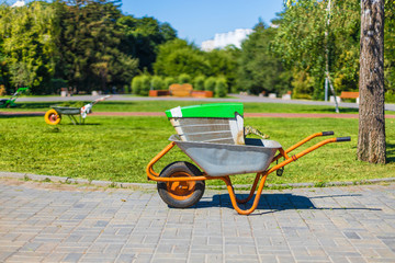 Obraz na płótnie Canvas Wheelbarrow on a green grass field. Garden metal wheelbarrow cart.