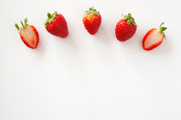 Arc of whole and half strawberries on white background. Isolated. Copy space.