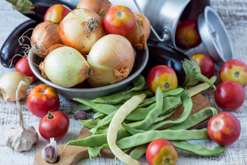 Fresh vegetables. Green bean pods, ripe red tomatoes, eggplants, onions and garlic on an old table. Selective focus.