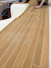 Ship building industry. Super sailing yacht. Assembling the wooden floor of the deck.
