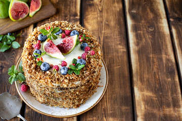 Carrot cake decorated with berries and figs on a wooden background. Traditional donkey pastries. Copy space.