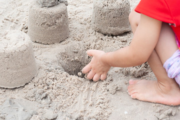 Unidentified children play sand castle on beach in summer season.