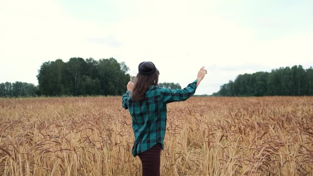 The girl uses glasses or VR headset outdoors among a wheat field. Future technologies, 3D graphics, virtual and augmented reality, concept