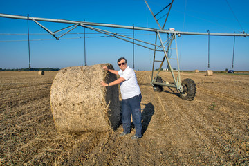 Farmer next to bale straw and irrigation system