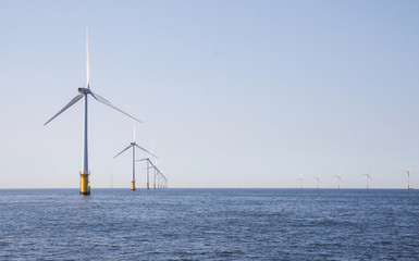 Wind turbines in an offshore wind farm in the North Sea just off the coast of the Netherlands, on a clear day.