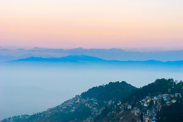 View of the mist-covered mountains and the city on the slopes of the mountains immersed in greenery