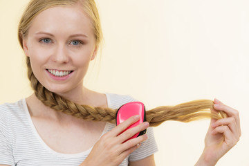 Blonde girl with long braid hair holds brush