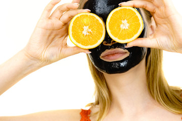 Girl black carbo mask on face holds orange fruit