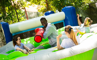 Funny friends playing on an inflatable trampoline in an amusement park. High quality photo