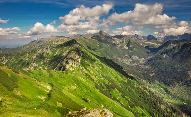 High Mountain style landscape with blue cloudy sky. Alpine scenery with green valley and rocky summits. Tatra Mountains in the summer.