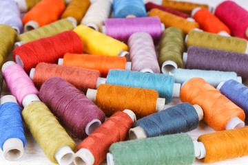 Multicolor sewing threads on white wooden background