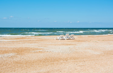 three empty sun loungers on an empty beach