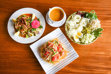 Asian Thai food top view with Thai rice noodles , curry Papaya salad , shrimp salad food served on wooden table setting plate /