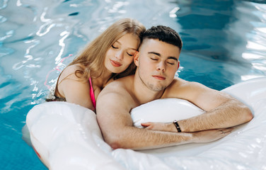 Amazing couple swims in the pool on an air mattress