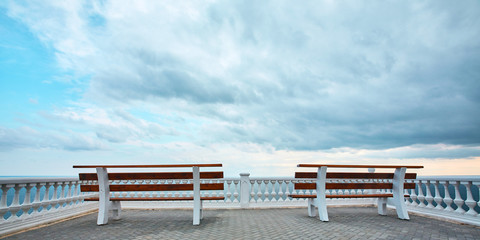 Viewing platform with bench. Empty promenade. Stormy dark sky. Virgin nature. Summer view. Ocean scenery.