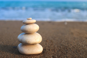 Fototapeta premium Zen stones. Concept of harmony, stability, life balance, relaxation and meditation. Pyramid of stones on the seashore. Copy space for text, selective focus, blurred