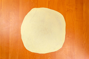 Pizza dough with tomato sauce on a rustic table