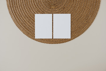 Blank paper cards with mockup copy space and wicker napkin on beige background. Minimal business...