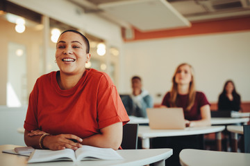 Smiling female student sitting in university classroom