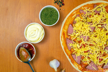 Pizza dough with tomato sauce on a rustic table