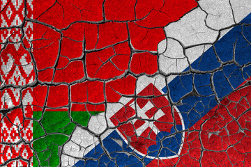Flags of Belarus and Slovakia on a cracked wall, dry land. Concept of relationship or conflict between countries	