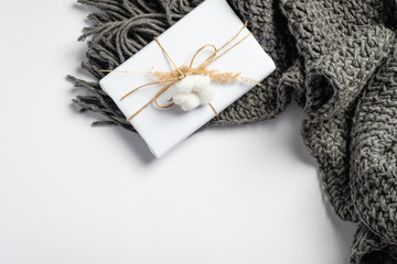 Autumn composition. Feminine desk table with knitted scarf and gift box on white background. Flat lay, top view. Nordic, hygge, cozy home concept