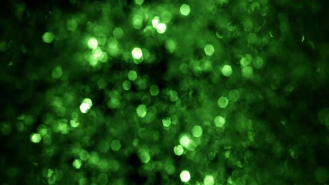 Full frame defocused and Bokeh snow and tinsel glow. Looped festive green and white gala glitter abstract bokeh background for St Patrick, Christmas New Year and party concepts