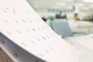 Close up white paper desk calendar on table with blurred office interior background