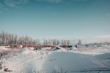 View of a snowy winter quarry in front of a forest.
