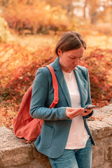 Businesswoman using mobile phone in autumn park