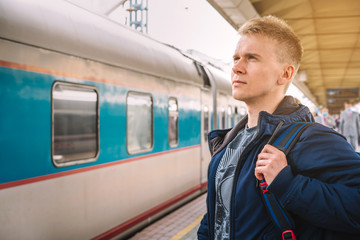 Moscow / Russia - 15 Aug 2020:  A young man with a backpack is standing on the platform at the railway station waiting to Board the train