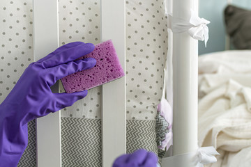 Woman hand in purple glove cleaning furniture in the room. Cleaning and disinfecting concept