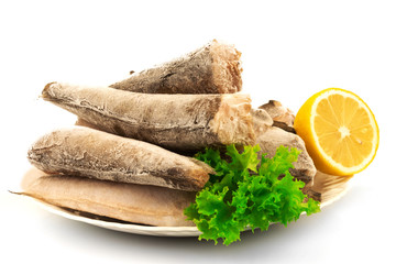 Frozen raw fish hake, pollock on the plate with lemon and leaves of salad lettuce isolated on white background. - 373458056