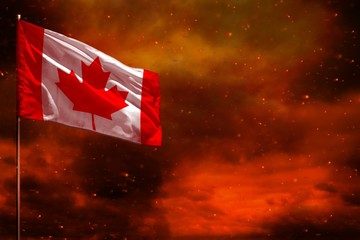 Fluttering Canada flag mockup with blank space for your text on crimson red sky with smoke pillars...