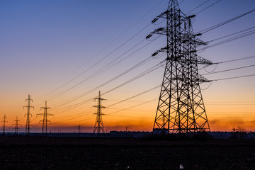 Fototapeta premium High voltage power line in a field at sunset