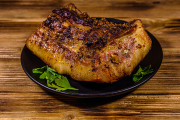 Baked piece of pork belly and parsley on a black plate