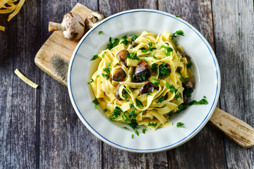 Italian food . Fresh home made  tagliatelle vegetarian  egg pasta  with mushrooms ,parmesan cheese ,fresh parsley  and black pepper.