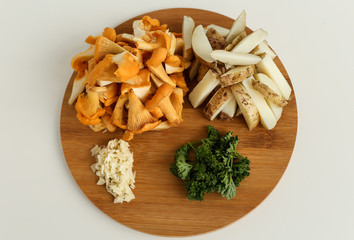 Ingredients for delicious fried potatoes with chanterelles and onions in a black plate with a fork on a wooden stand in the form of a rabbit