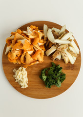 Ingredients for delicious fried potatoes with chanterelles and onions in a black plate with a fork on a wooden stand in the form of a rabbit