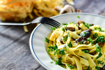 Italian food . Fresh home made  tagliatelle vegetarian  egg pasta  with mushrooms ,parmesan cheese ,fresh parsley  and black pepper.
