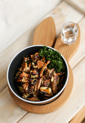 Delicious fried potatoes with chanterelles and onions in a black plate with a fork on a wooden stand in the form of a rabbit
