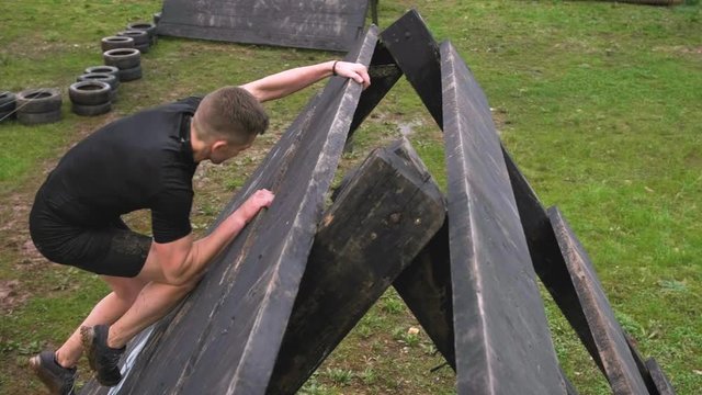 Male participant in an obstacle course climbing a pyramid obstacle