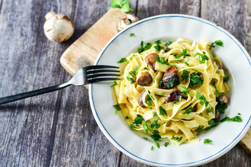 Italian food . Fresh home made  tagliatelle vegetarian  egg pasta  with mushrooms ,parmesan cheese ,fresh parsley  and black pepper.