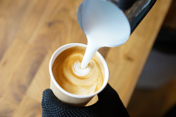 Barista prepares coffee in a paper cup