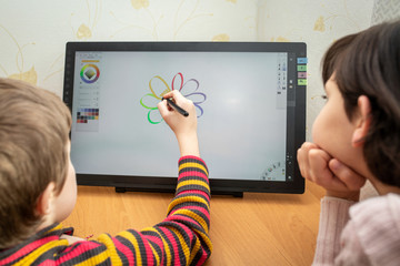 Children draw a color flower on a graphics tablet.